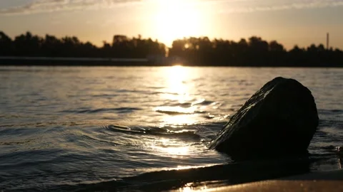 Close up sunrise reflected in the water, river bank. Backlight. Video stock 136880703