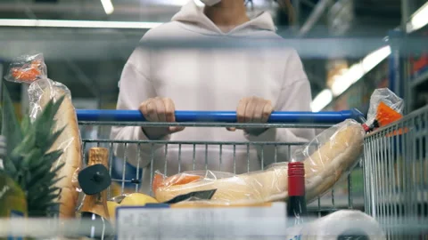 Close up of a supermarket trolley being pulled by a woman Vidéo 156750680