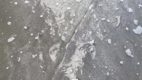 Close-up the surface of the beach waves flowing over the gray beach sand Stock Footage 295567546