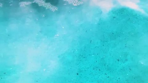 Close up surface of blue water on textured floor with smoke and bubbles in pool Stock Footage 315294364