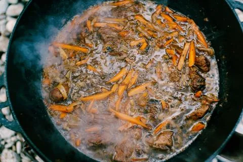 Close-up of the surface of the finished pilaf in a cauldron on fire. Orange Stock Photos