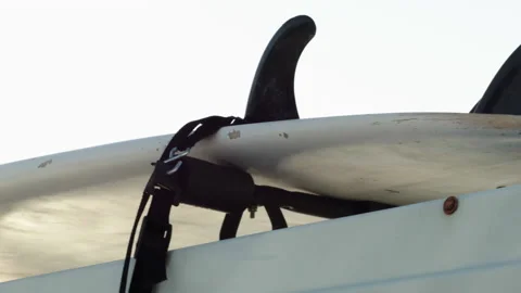 Close-Up of Surfboard Strapped on top of Car Stock Footage 185097695