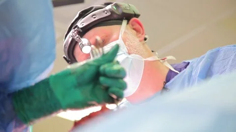 Close-up of a surgeon's face. hands in rubber gloves during surgery Stock Footage 77438699