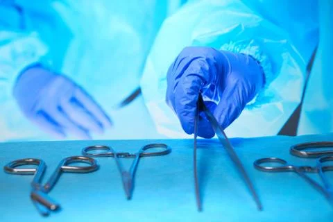 Close-up of of surgeons hands at work in operating theater toned in blue 库存照片