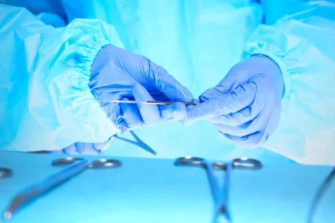 Close-up of of surgeons hands at work in operating theater toned in blue Stockfoto's