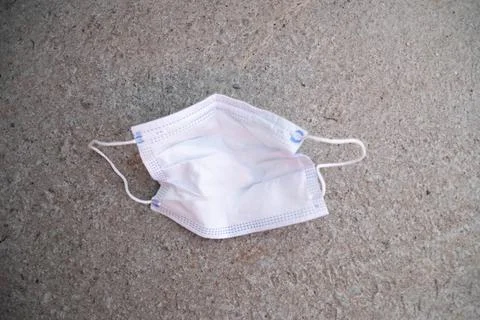 Close up on a surgery mask trash it on the ground upside down Stock Photos