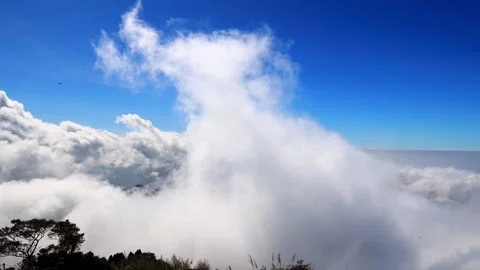 Close up of  the surging blue sky, churning sea of clouds above peak.4K Stock Footage 258762996