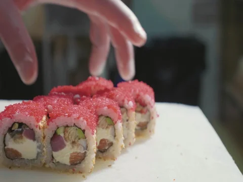 Close-up of sushi chef in gloves puts the rolls on decorated plate. Stock Footage 82805170