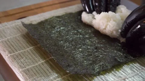 Close-up of the sushi chef's hands, spreading rice all over the nori area 库存影片 132037023