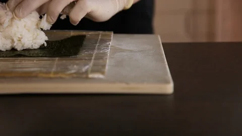 Close-up of sushi master spreads rice on nori.Sushi making process.Chef's hands Stock Footage 119861384