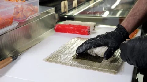 Close-up of sushi master spreads rice on nori. Sushi making process. Stock Footage 323363401