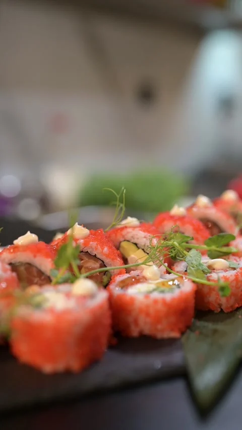 Close-up of sushi rolls coated in orange tobiko, topped with sauce and Stock Footage 314501959