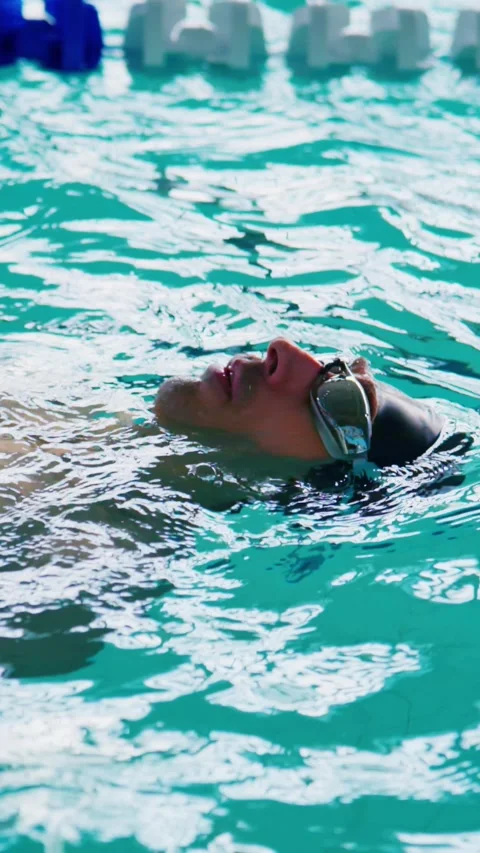 Close-up of swimmer relaxed face-up in clear water Stock Footage 346457888