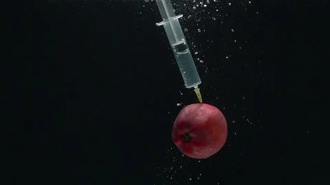 Close-up of a syringe and an apple falling into the water in a slow motion. Stock Footage 273079046