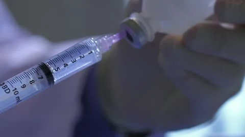 Close on syringe drawing from vial, transfer to bottle Stock Footage 20447571