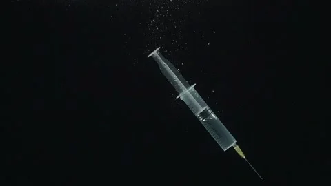 Close-up of the syringe falling into the water against a black background. Stock Footage 273078635