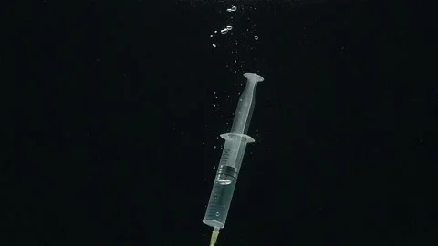 Close-up of the syringe falling into the water against a black background. Stock-Footage 273078657