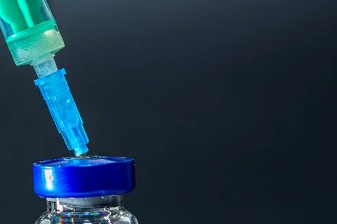 Close-up of a syringe needle inserting into a vial.  Medical injection prep.. Stock Photos