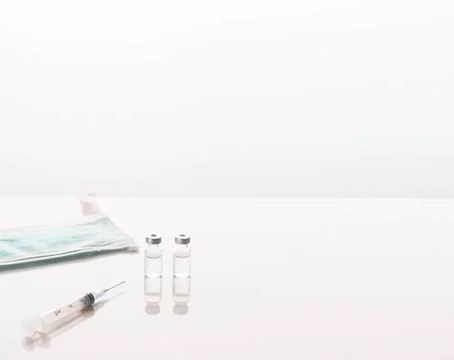 Close-up of a syringe with needle, two vials and a surgical mask Photos