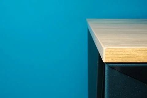 Close-up of a table corner solid wood furniture detail with blue background Stock Photos