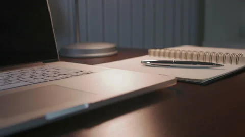 Close up of a table on which there is a laptop, a pen and a lamp. Video stock 58590972