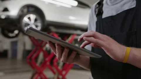 Close-up of a tablet in the hands of a mechanic. Diagnostics and repair of cars Stock Footage 212059909