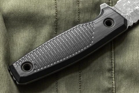 Close-up of a tactical knife handle made of black micarta placed on green m.. Stock Photos