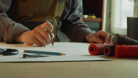 Close-up tailor makes markings on a sheet of paper with a pencil and compasses 스톡 사진