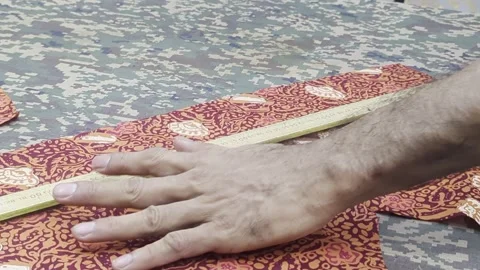 Close Up of Tailor Measuring Traditional Batik Fabric with Tape Measure Stock Footage 328973461