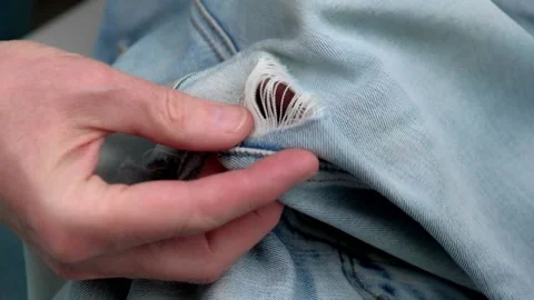 Close-up of the tailor's hands checking the holes rubbed between legs on jeans. Stock Footage 197397405