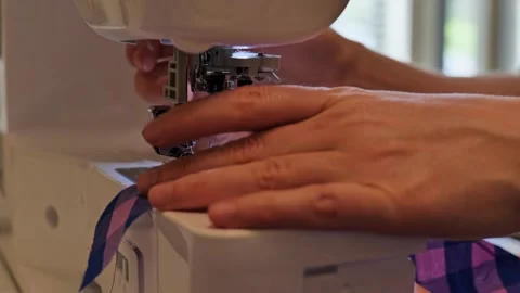 Close-up of a tailor's hands using a modern sewing machine to stitch fabric Stock Footage 340930083