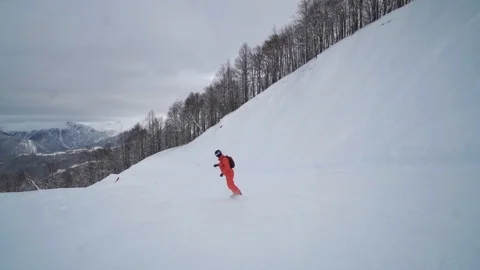 Close take of a guy dressed in organge riding down an empty ski track Video stock 101788056