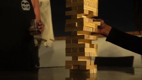 Close-up taking out a wooden block with the hands of a well-known board game at Vidéo 173517671