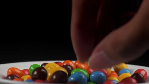 Close up of taking peanut chocolate candies one by one in white plate Stock Footage 279039441