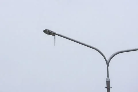 Close-up of a tall pole with a lantern from which a large dangerous ice ici.. Stock Photos