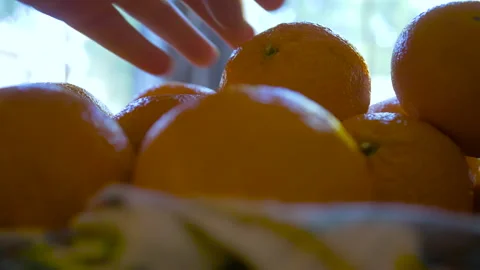Close up of tangerines in basket as woman picks one up Stock Footage