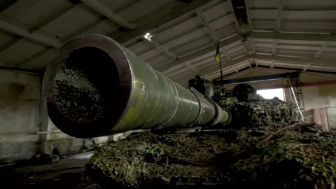 A close-up of the tank's muzzle slowly turns to the side. Tank in a hangar in Stock Footage 237043465