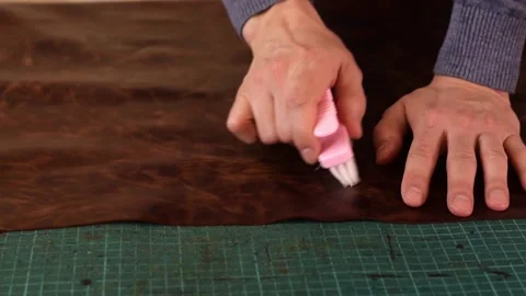 Close-up of a tanner's hands brushing a sheet of brown leather Stock Footage 150477649