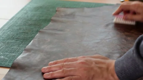 Close-up of a tanner's hands brushing a sheet of brown leather. Stock Footage 150477764