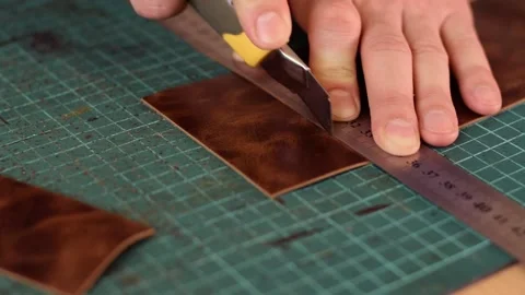 Close up of tanner's hands measuring and cutting leather with knife. Stock Footage 150477536