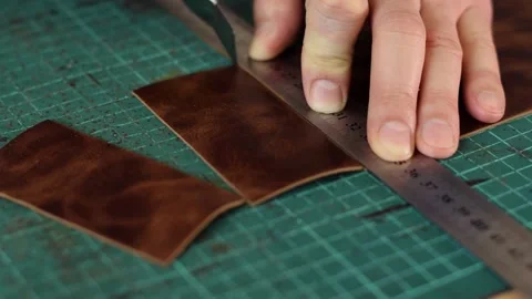 Close up of tanner's hands measuring and cutting leather with knife. Stock Footage 150477539