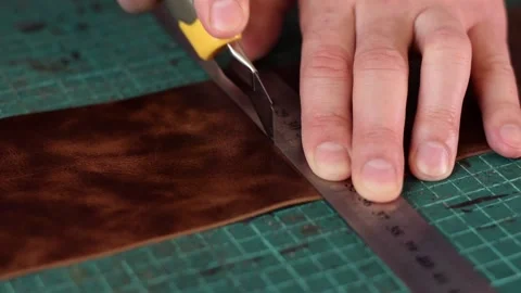 Close up of tanner's hands measuring and cutting leather with knife. Stock Footage 150477556