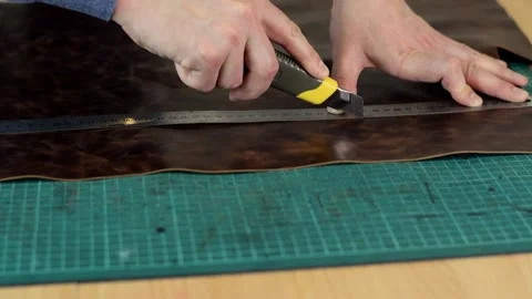 Close up of tanner's hands measuring and cutting leather with knife. Stock Footage 150477594