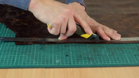 Close up of tanner's hands measuring and cutting leather with knife. Stock Footage 150477637