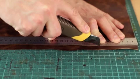 Close up of tanner's hands measuring and cutting leather with knife. Stock Footage 150477748