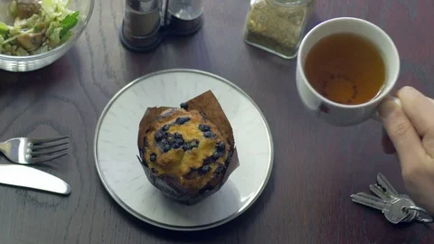 Close-up of tasting a herbal tea and a cupcake in the morning Stock Footage 75460366