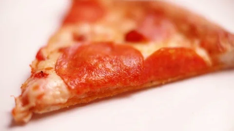 Close-up of tasty pepperoni pizza slice in a clean white plate. Rack focus Stock Footage 123660795