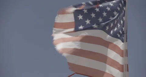 Close Up Tattered American Flag Waving Against Blue Sky Stock Footage 89943058