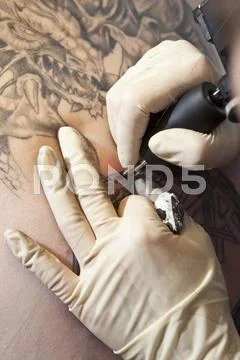 Close-up of a tattoo artist tattooing a design on human skin Stock Photos