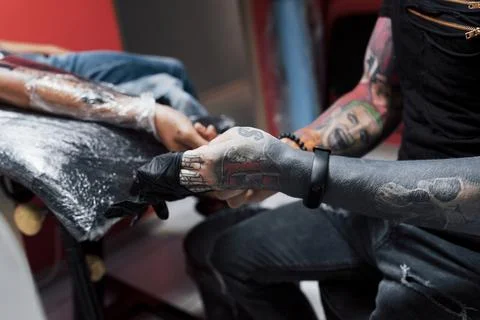 Close up tattoo machine. Master in black sterile gloves creating picture on.. Stock Photos